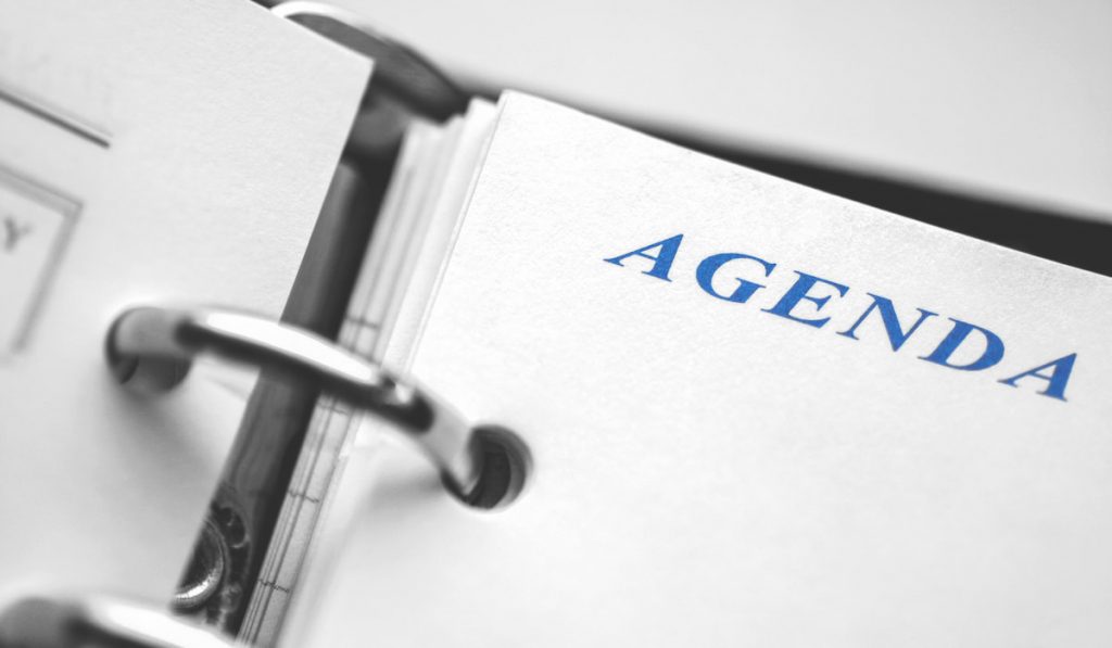 Daily agenda paper planner closeup. Black and white picture with blue word Agenda 