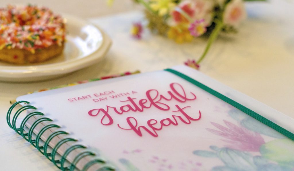 Grateful heart journal with donut and flowers on the table