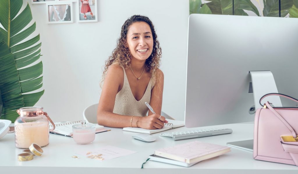 Smiling woman writing in her journal in office