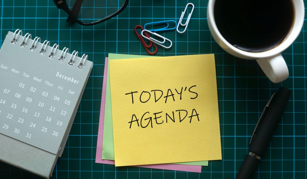 Today's agenda on sticky note with calendar and coffee on the table