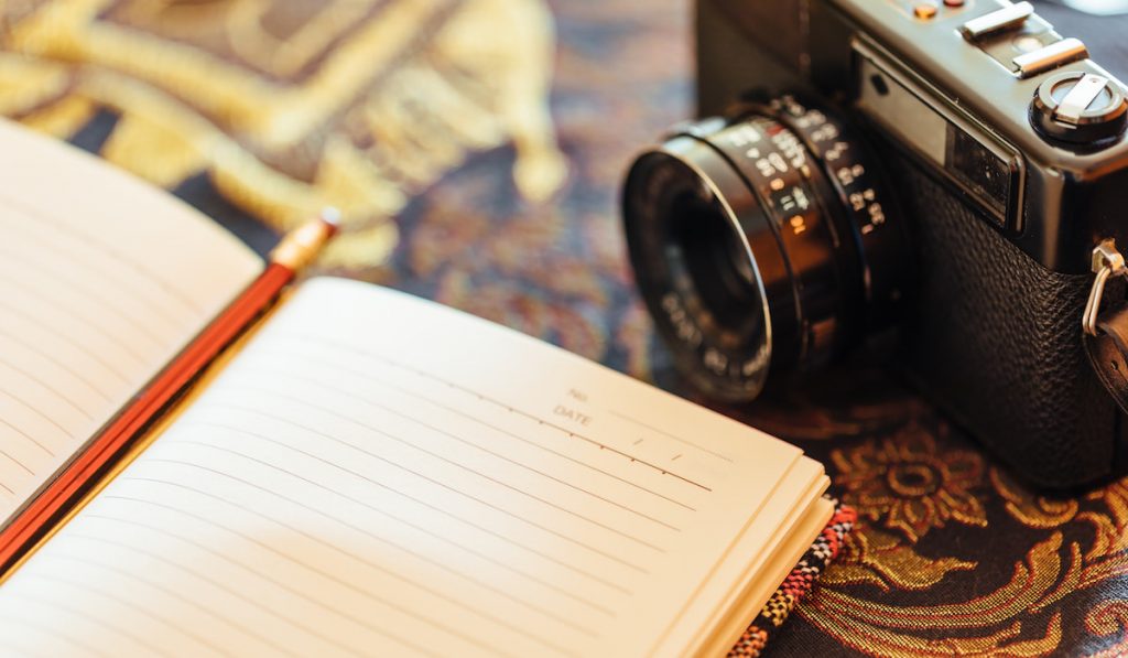 blank open journal next to a vintage camera