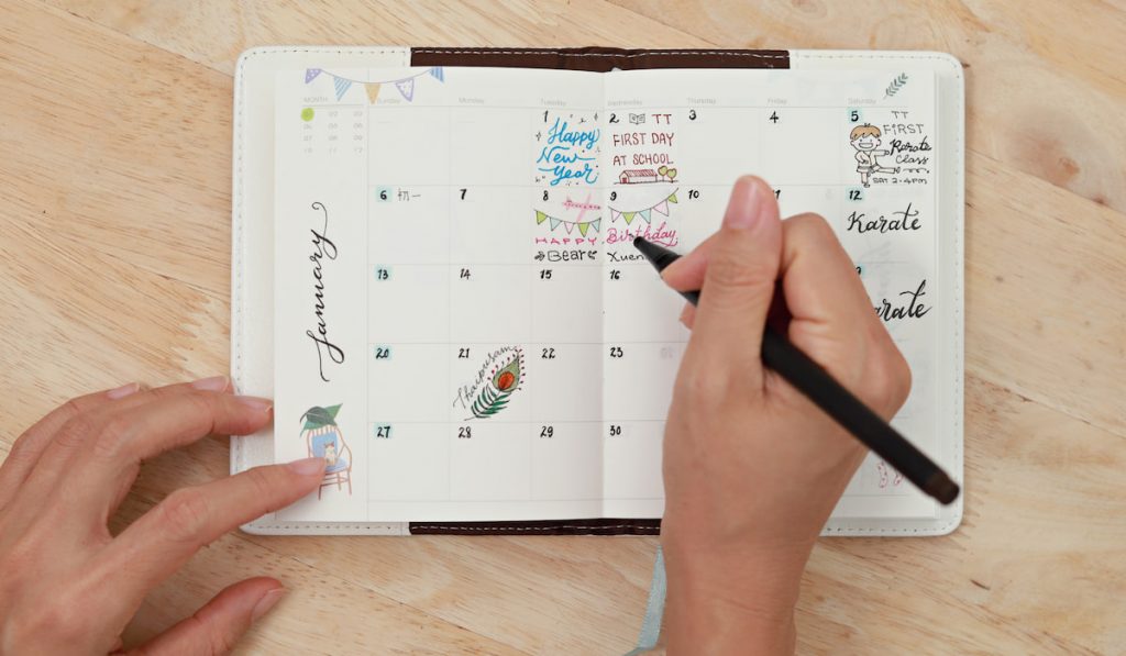 female hand holding pen writing on planner