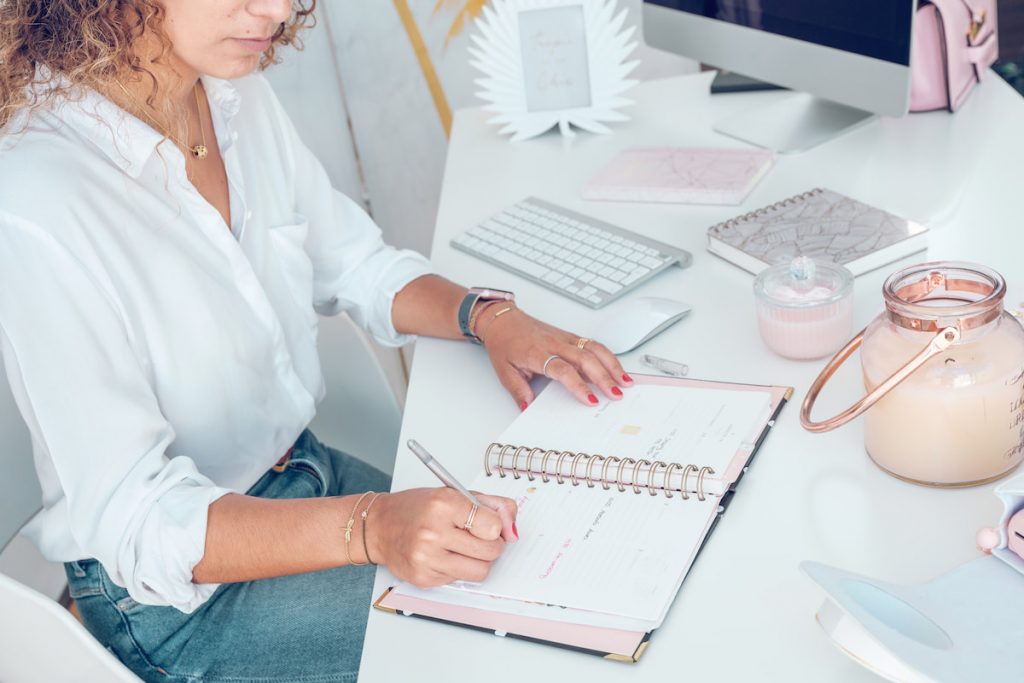 female sitting at table and writing notes in planner in office