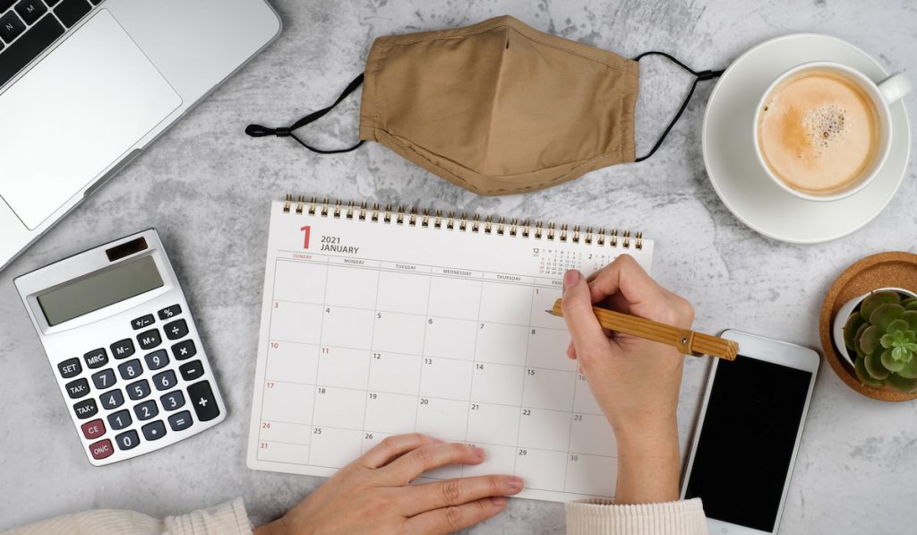 woman is writing on planner and Calendar for2021 with phone coffee and laptop