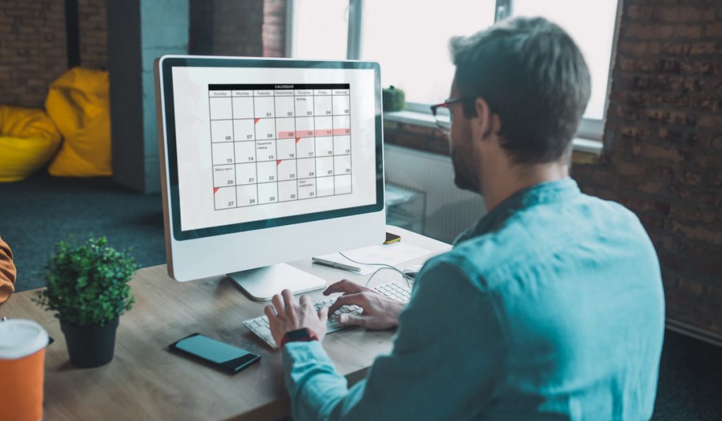 man checking his calendar schedule on his computer