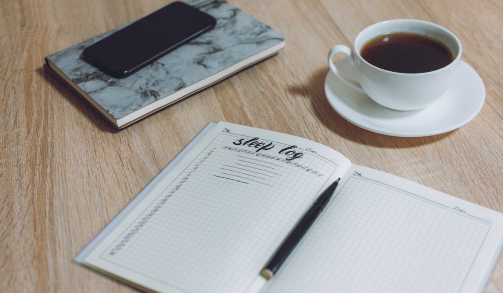 sleeping log using grid notebook and coffee on the table 