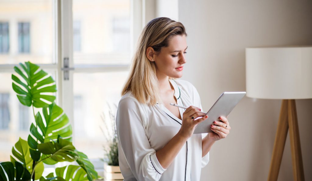 woman writing on her tablet updating her planner 