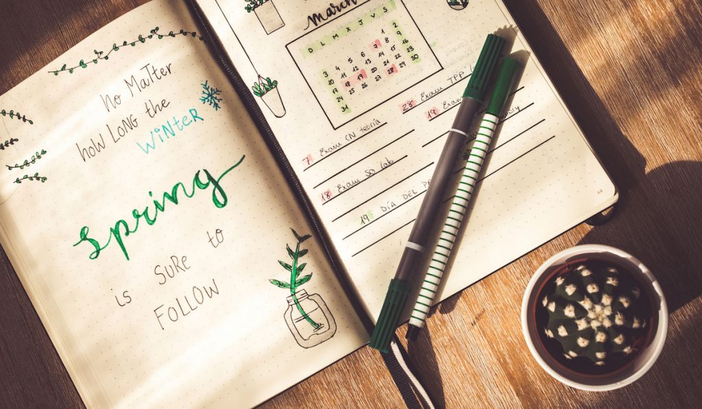 Spring quote lettering in a bullet journal on wooden table