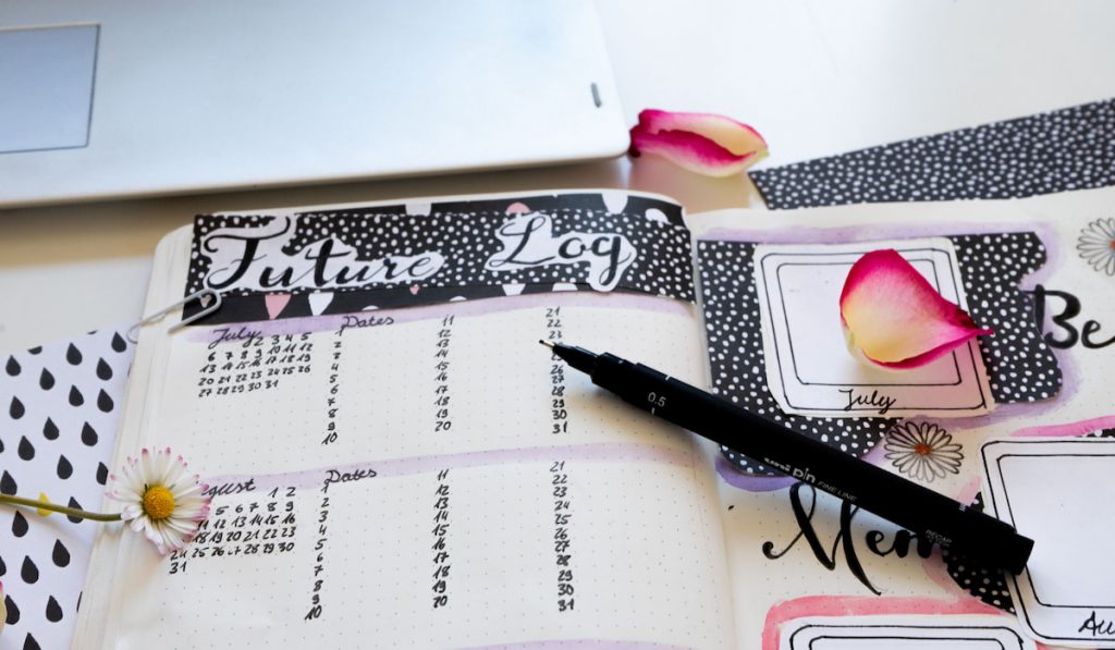 bullet journal - close up of future log and best memory page in notebook surrounded by rose leaves